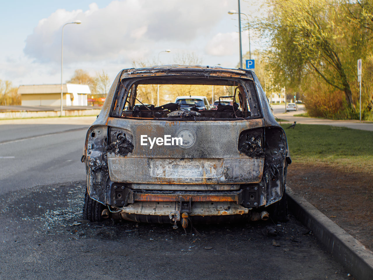 Close rear view to the burned car on the street during the day. selective focus on burned engine.