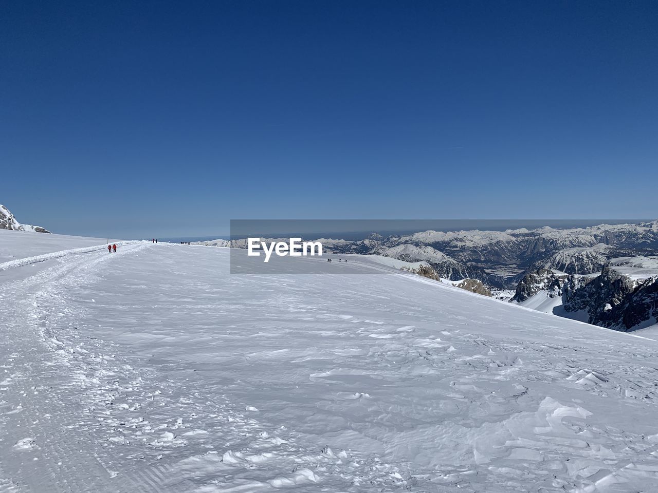 Snow covered landscape against clear blue sky