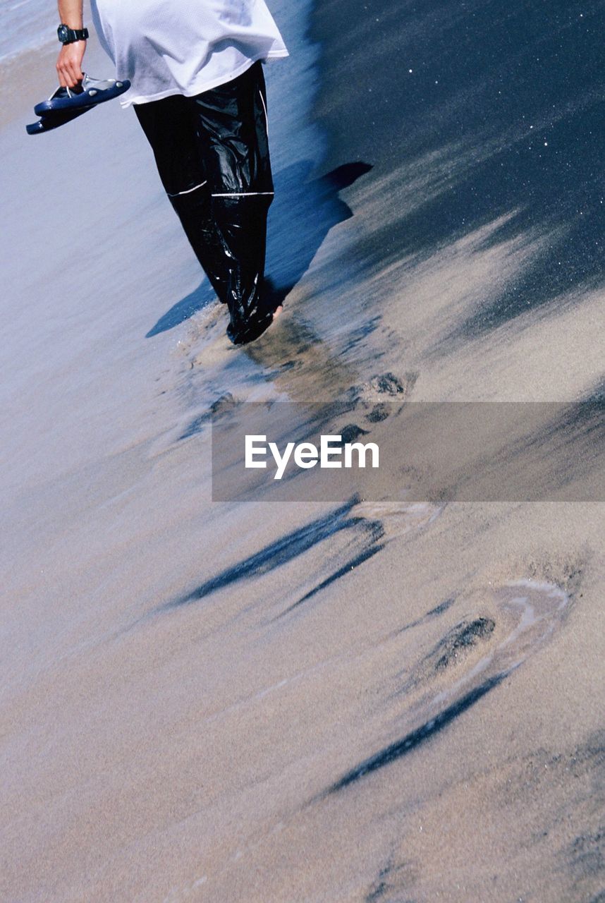 Low section of man walking on beach