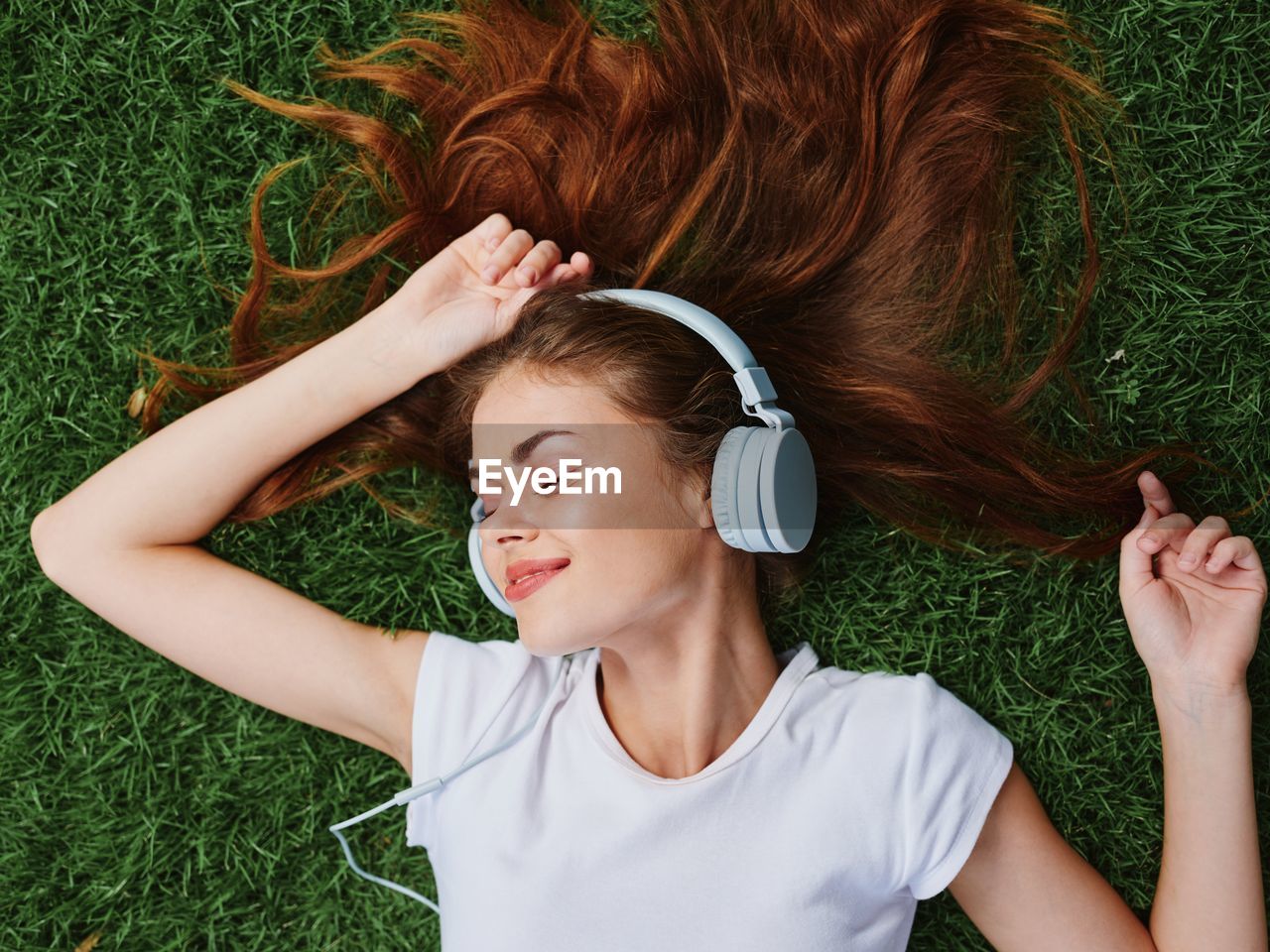 high angle view of young woman with arms raised on grassy field