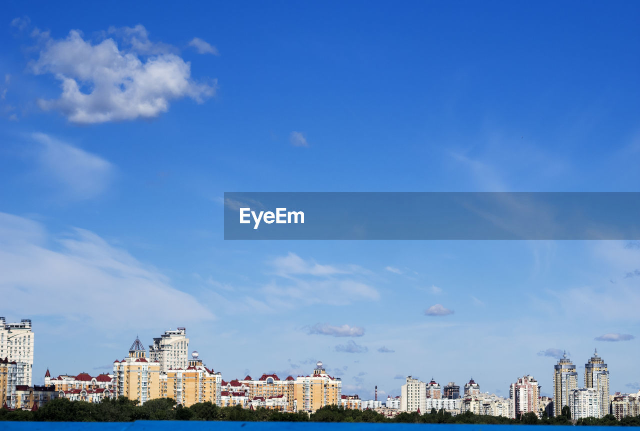 Dnieper river by buildings against cloudy sky