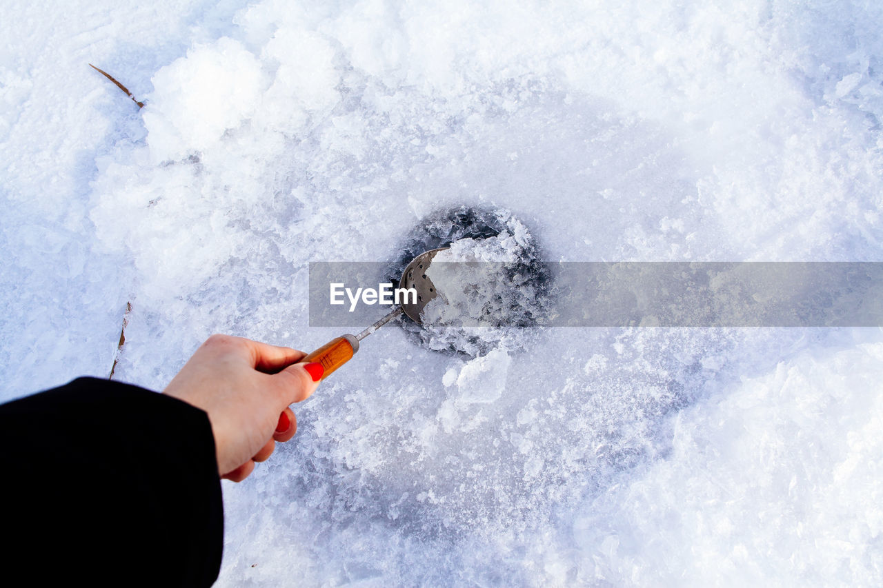 Cropped hand of woman cracking frozen ice outdoors