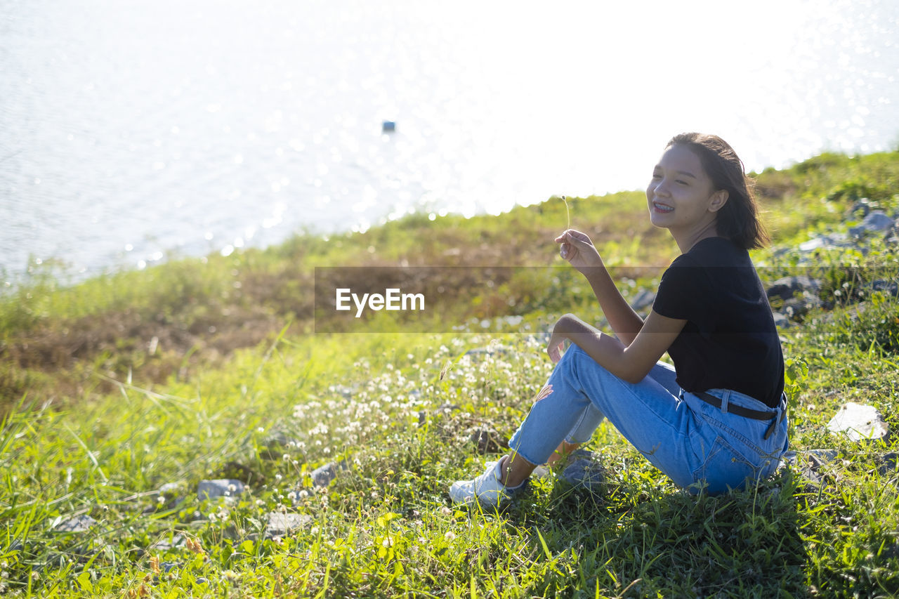 SIDE VIEW OF WOMAN SITTING ON GRASS