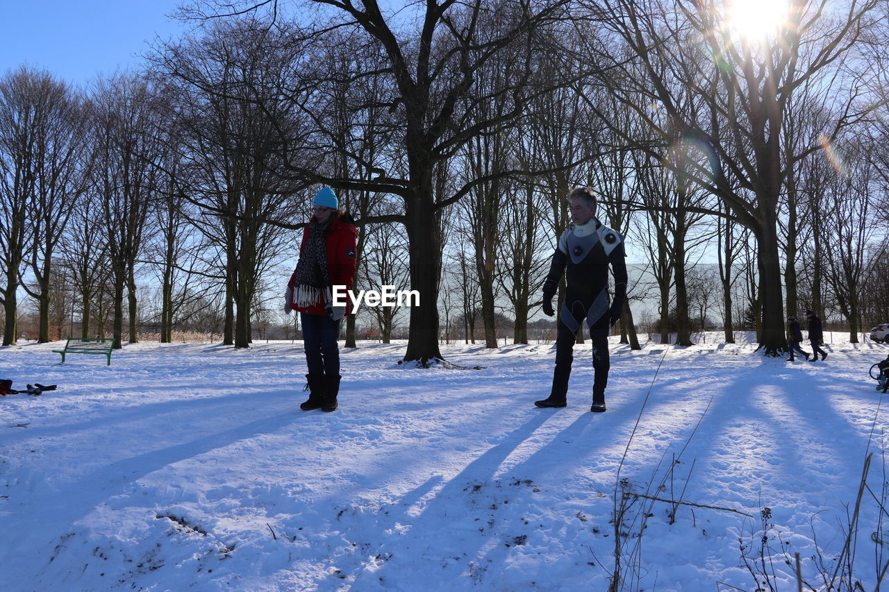 REAR VIEW OF MEN WALKING ON SNOW COVERED FIELD