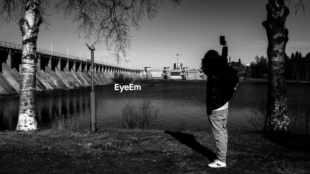 REAR VIEW OF WOMAN STANDING AGAINST SKY