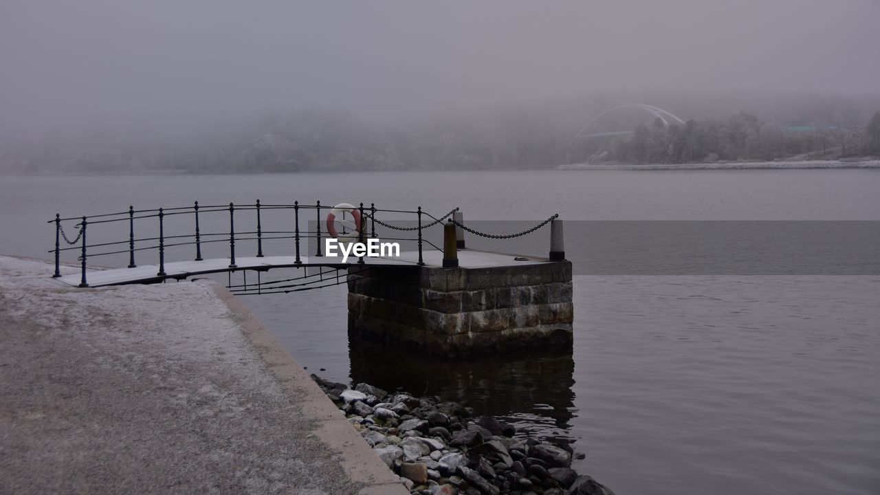 Built structure by sea against sky during winter