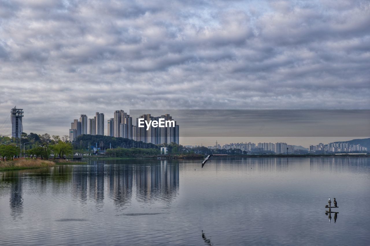 Scenic view of lake by buildings against sky in city