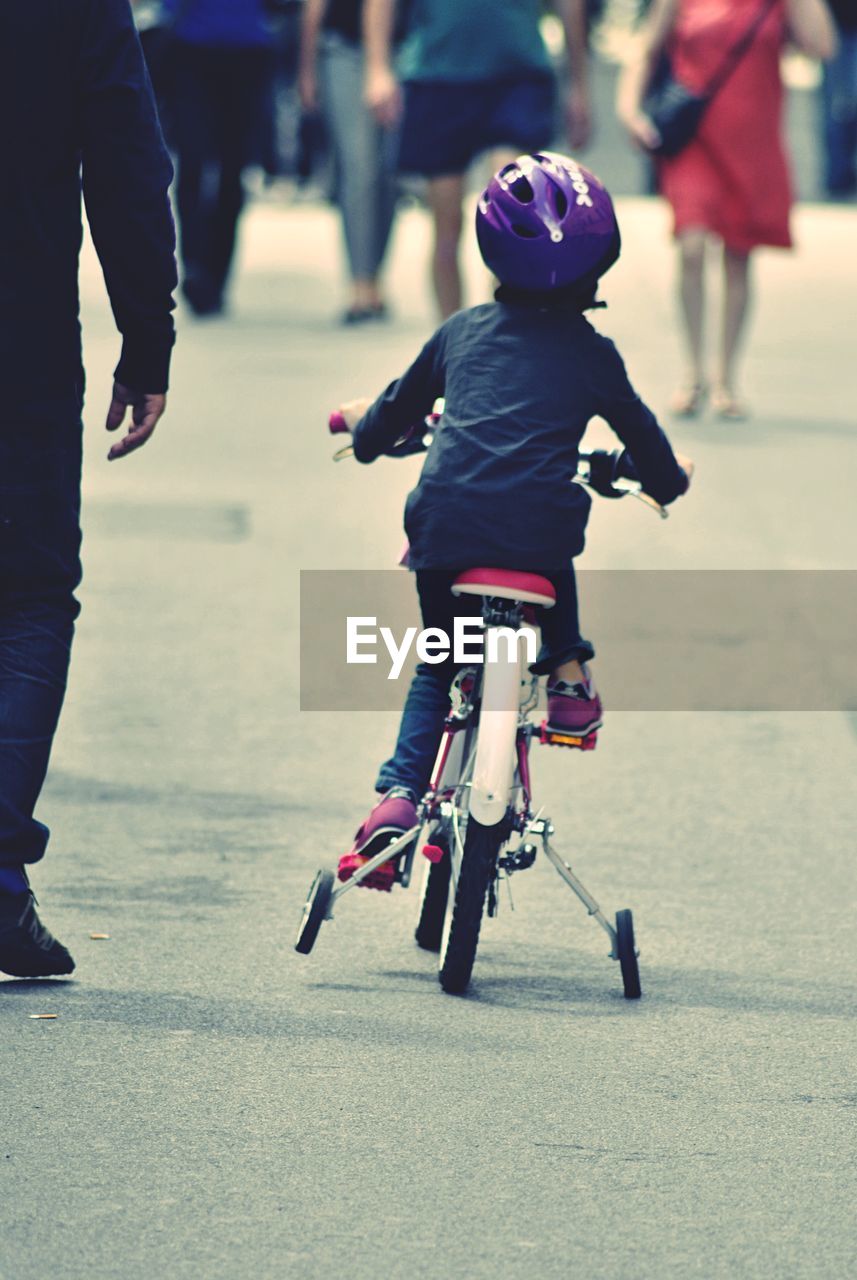 Rear view of girl cycling on road