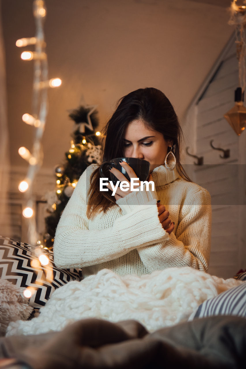 Woman drinking coffee in illuminated room