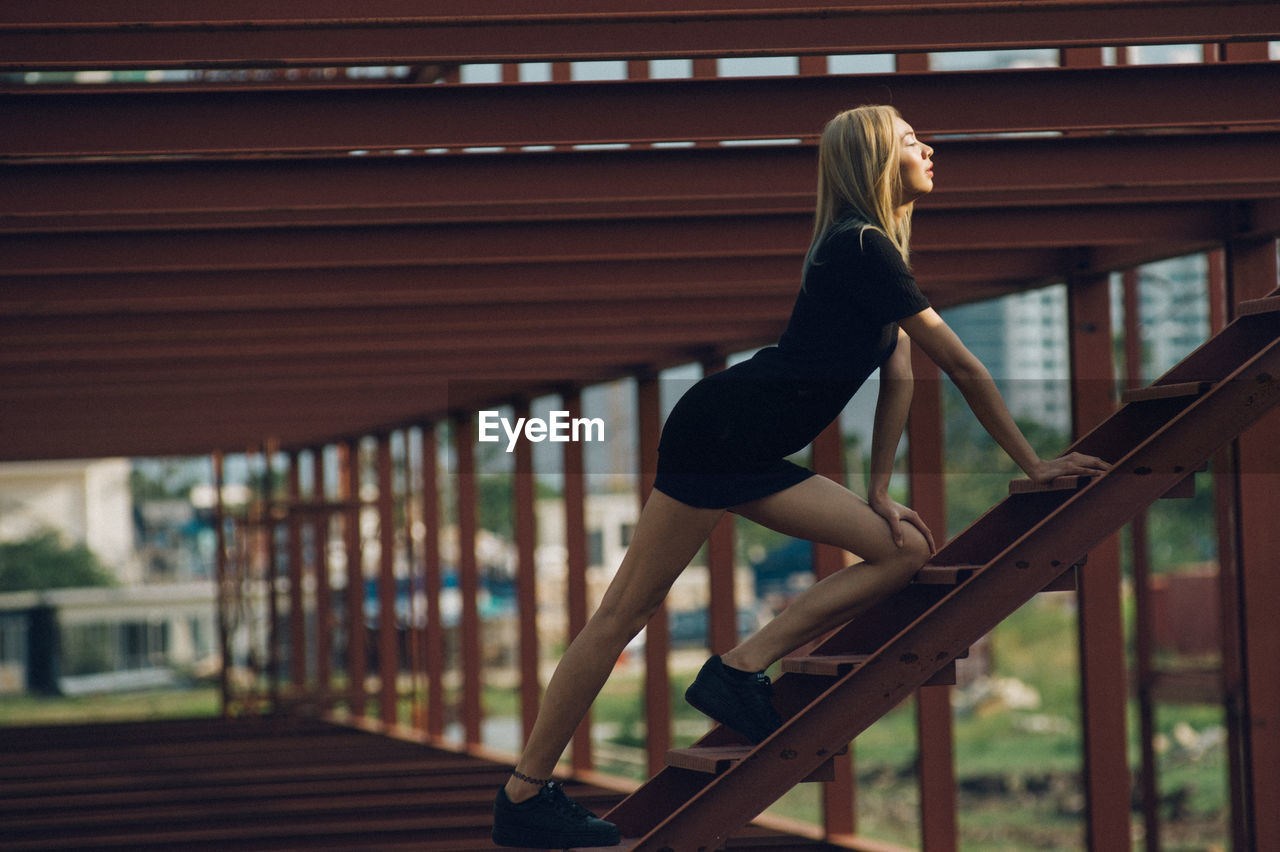 Side view of woman climbing wooden steps