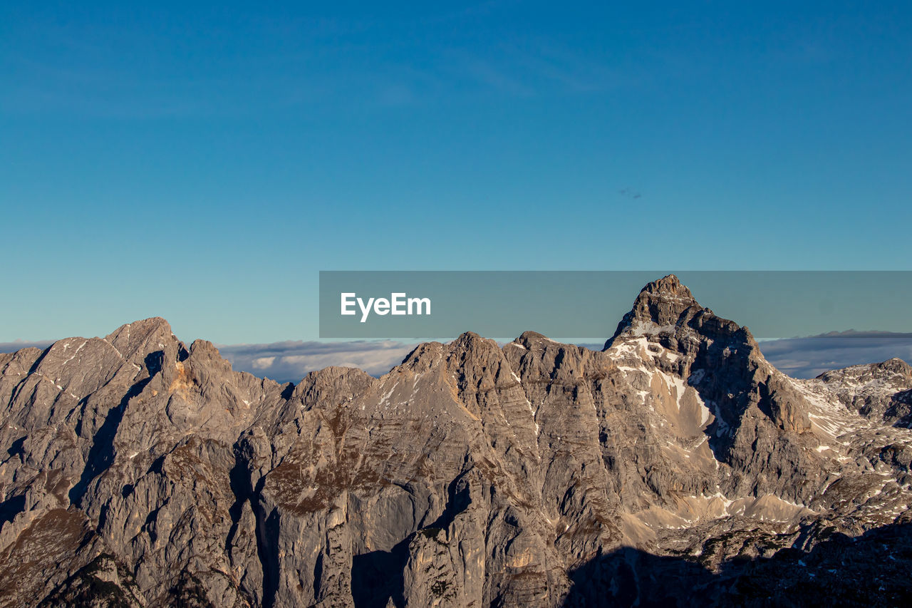 Panoramic view of snowcapped mountains against clear blue sky