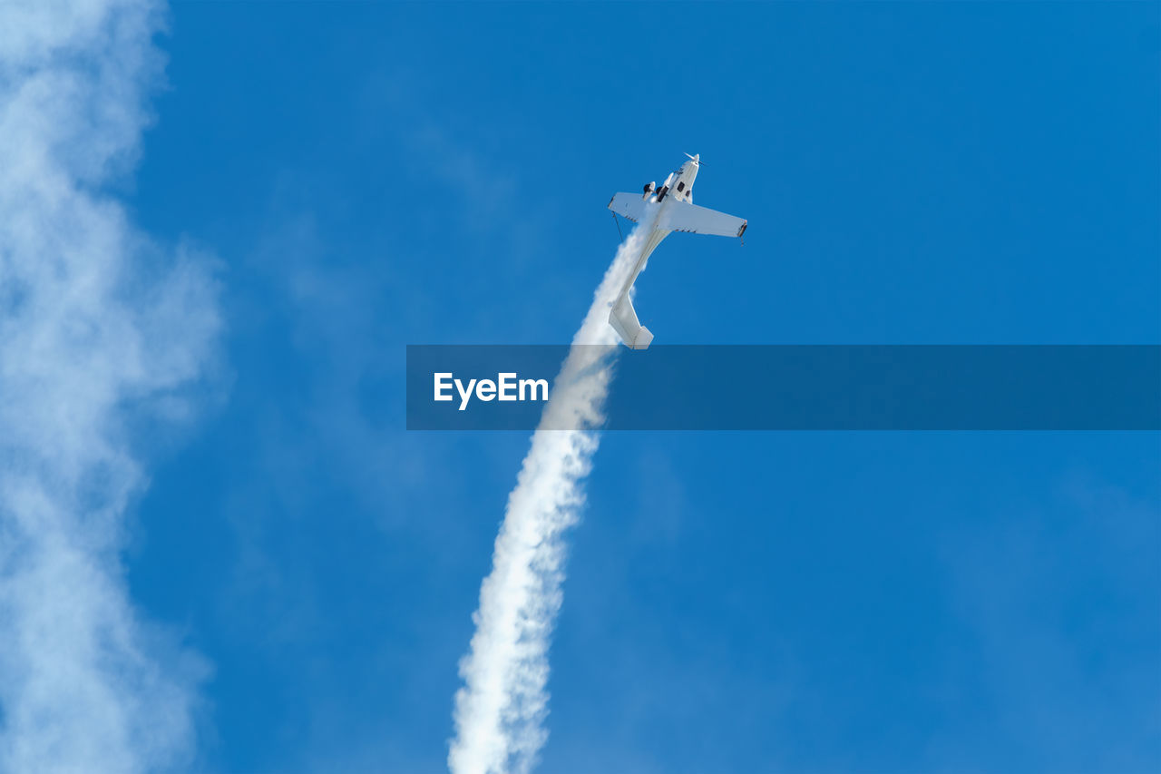 sky, cloud, air vehicle, airplane, vapor trail, flying, transportation, air show, mode of transportation, blue, on the move, smoke, low angle view, nature, day, motion, no people, vehicle, mid-air, outdoors, aerobatics, speed, plane, sunny, travel, fighter plane, stunt, performance, aircraft, clear sky, white, military, wing