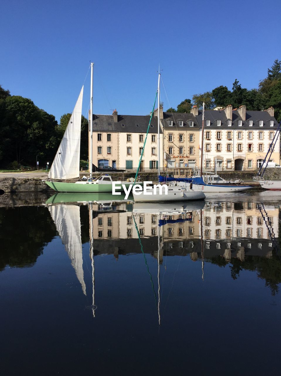 SAILBOATS MOORED IN LAKE AGAINST BUILDINGS