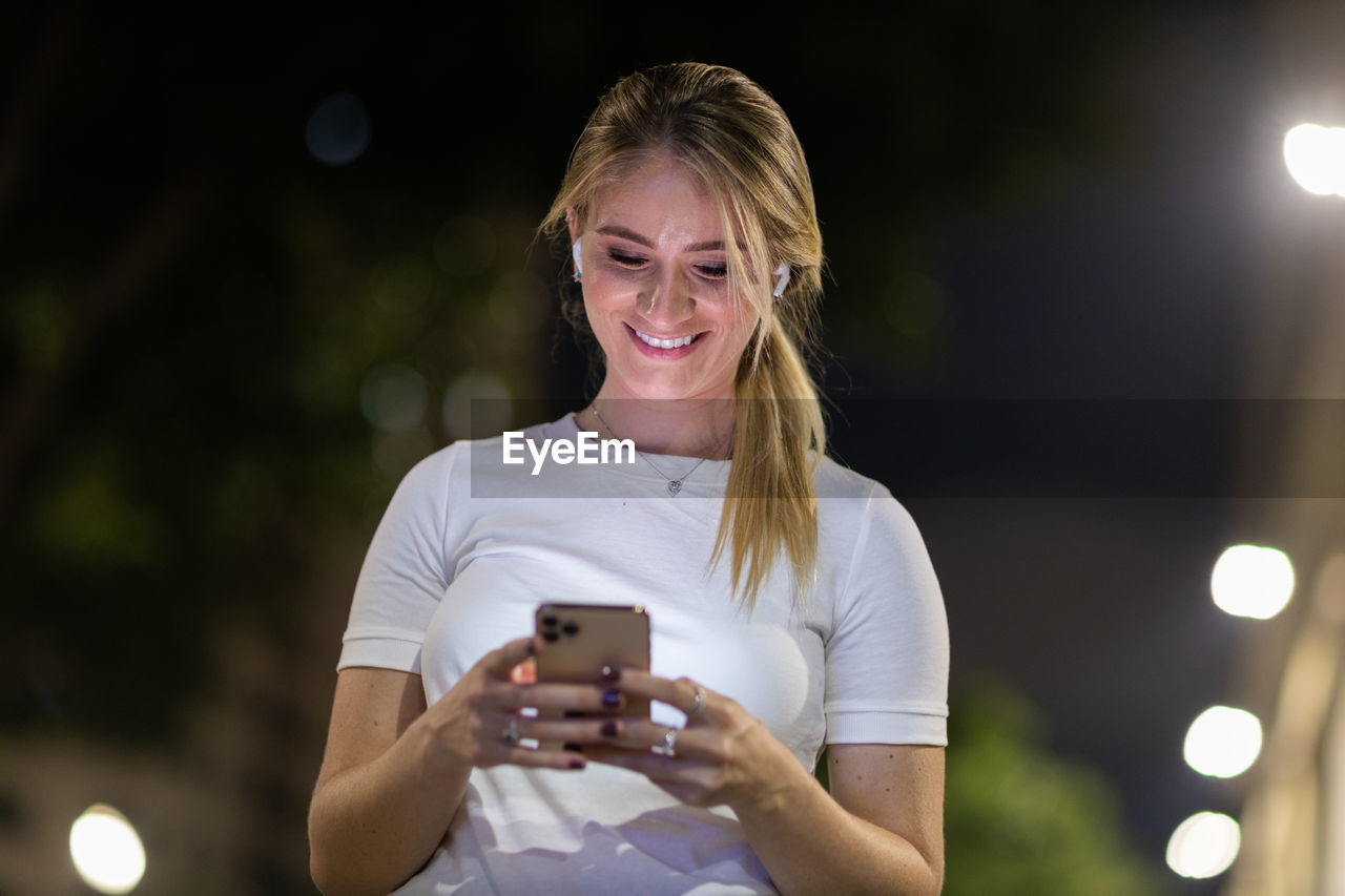 Woman using a smartphone at night time on the street. mobile phone, technology, urban .