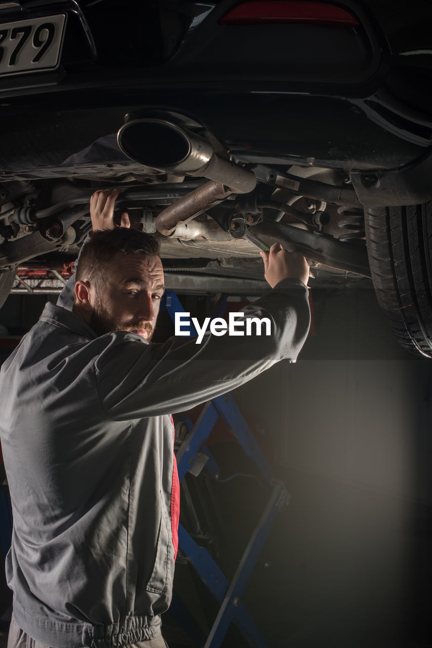 Portrait of male mechanic repairing car at auto repair shop