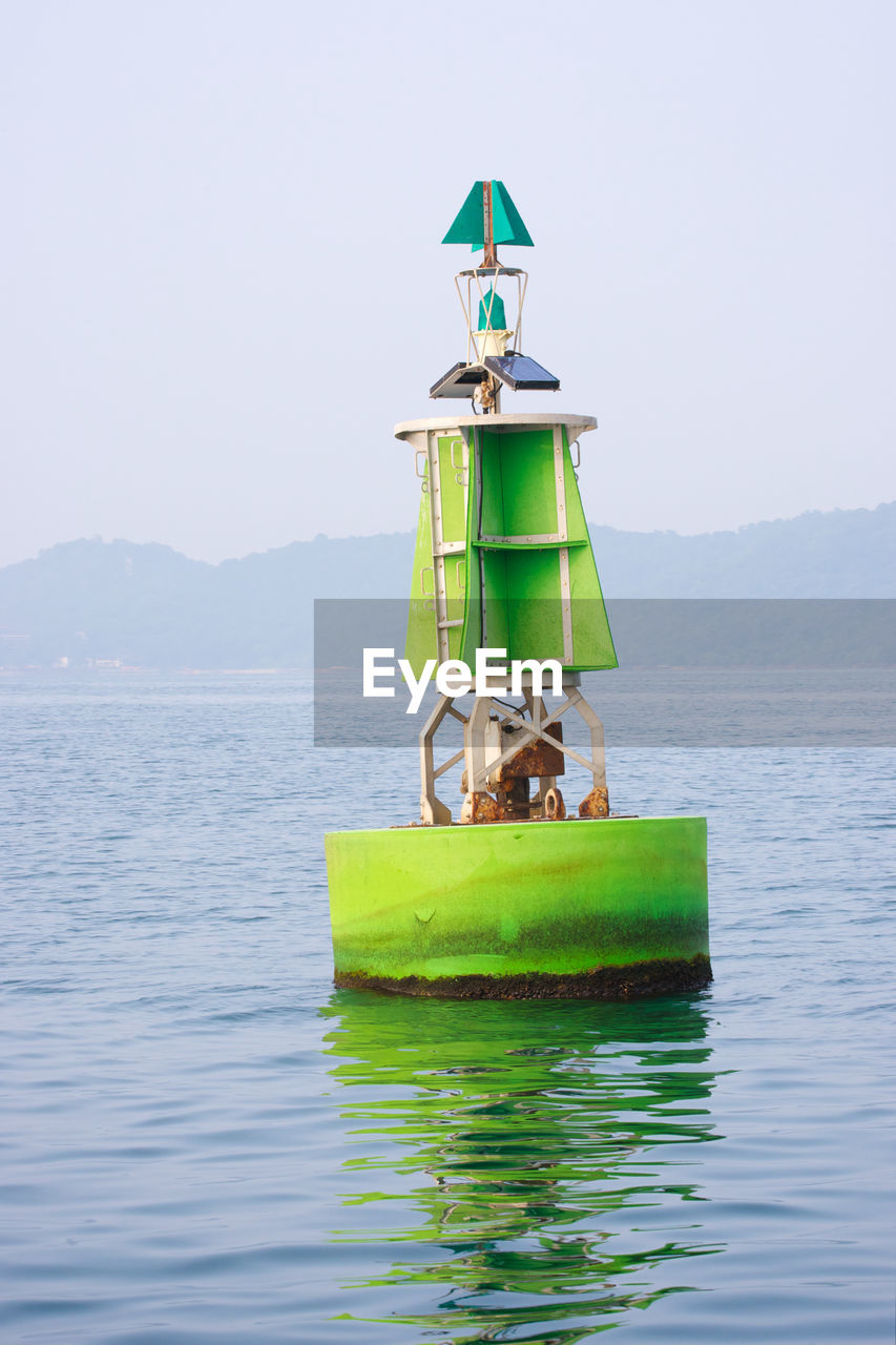 GREEN FLOATING ON SEA AGAINST SKY