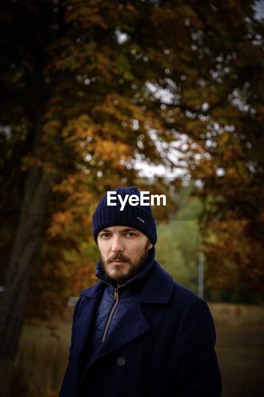 Portrait of man standing against trees in winter