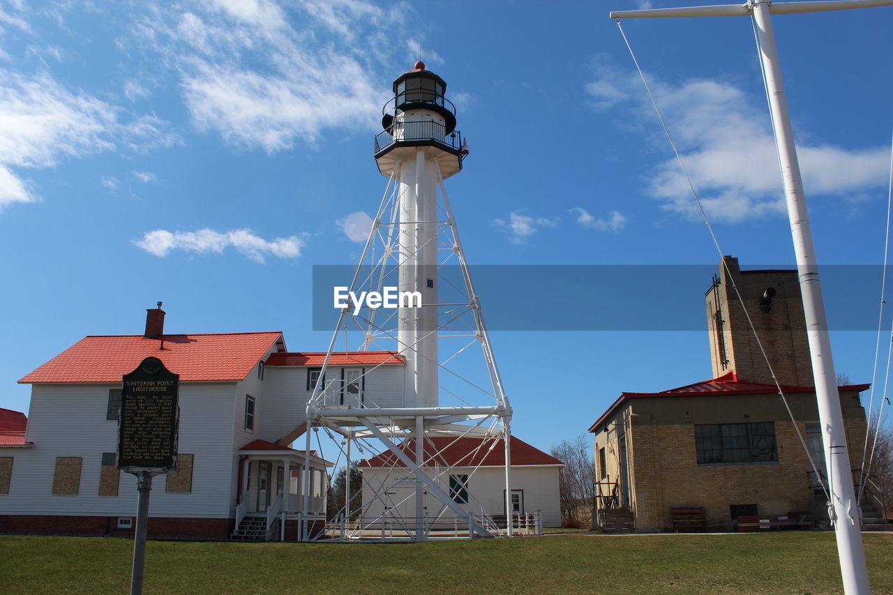 LOW ANGLE VIEW OF LIGHTHOUSE AGAINST BUILDINGS AND SKY