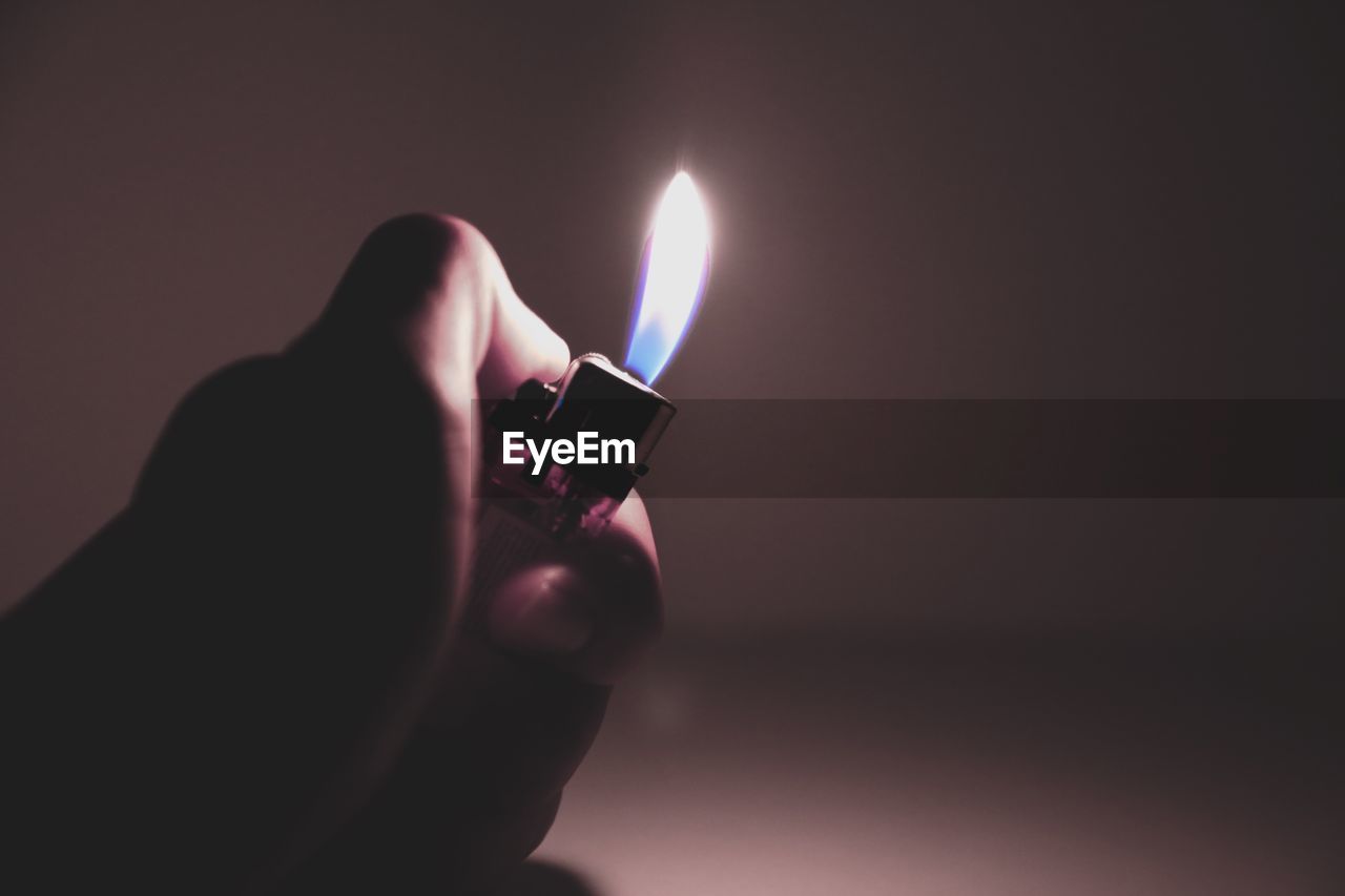 Close-up of hand holding lit candle