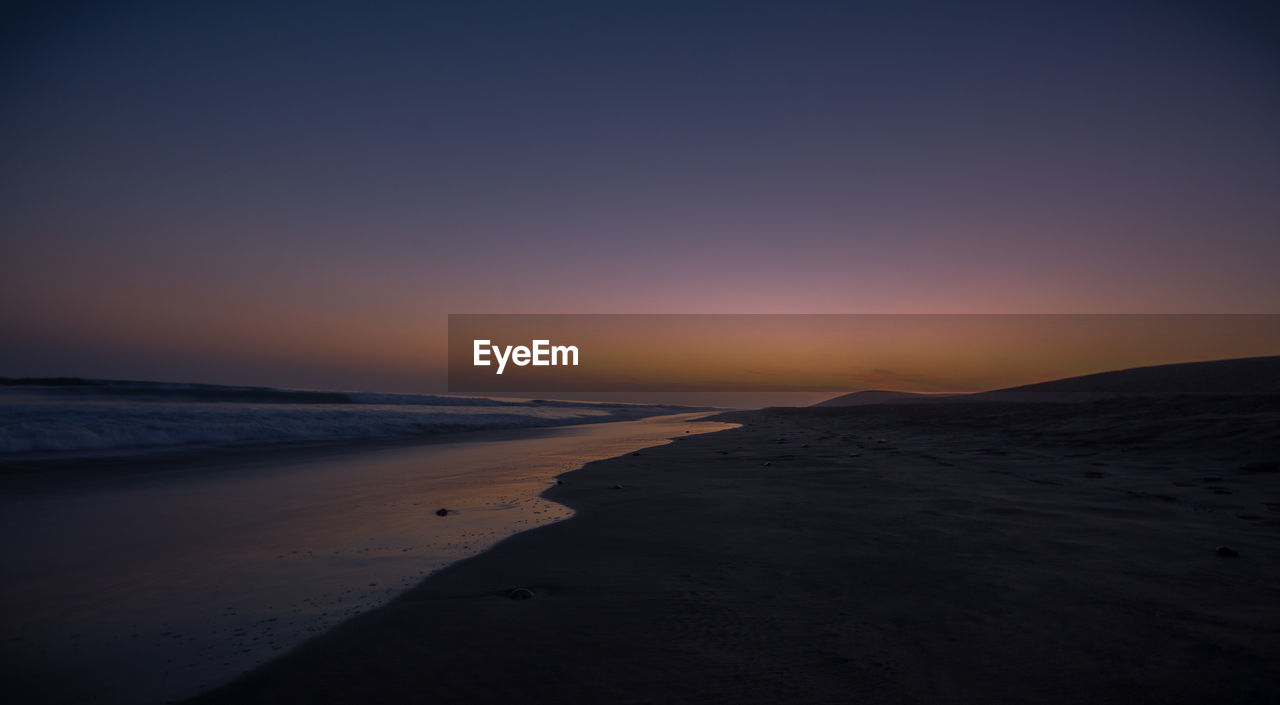 SCENIC VIEW OF BEACH AGAINST SKY DURING SUNSET