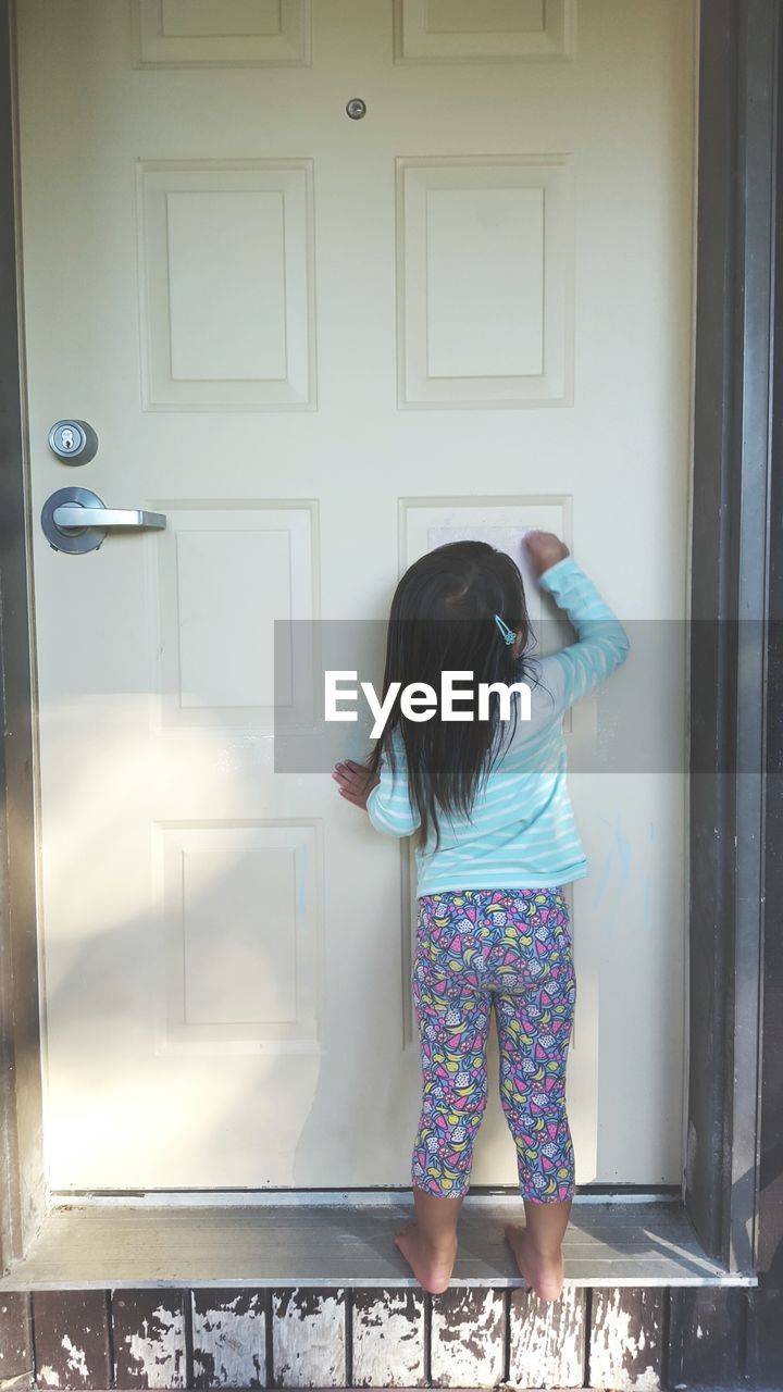 Rear view of girl knocking door