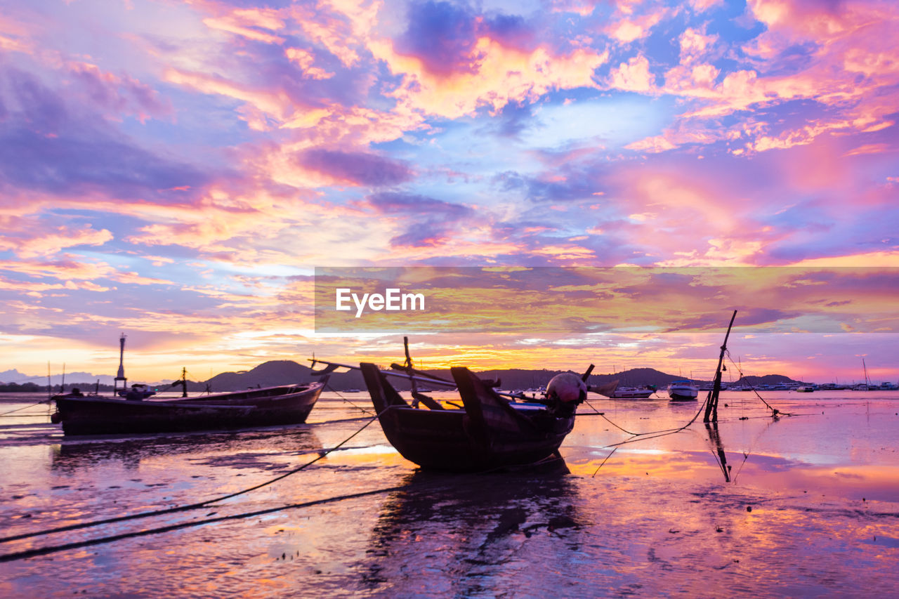 BOATS MOORED ON SEA AGAINST ORANGE SKY