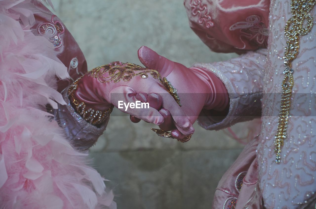 Midsection of couple holding hands during wedding ceremony
