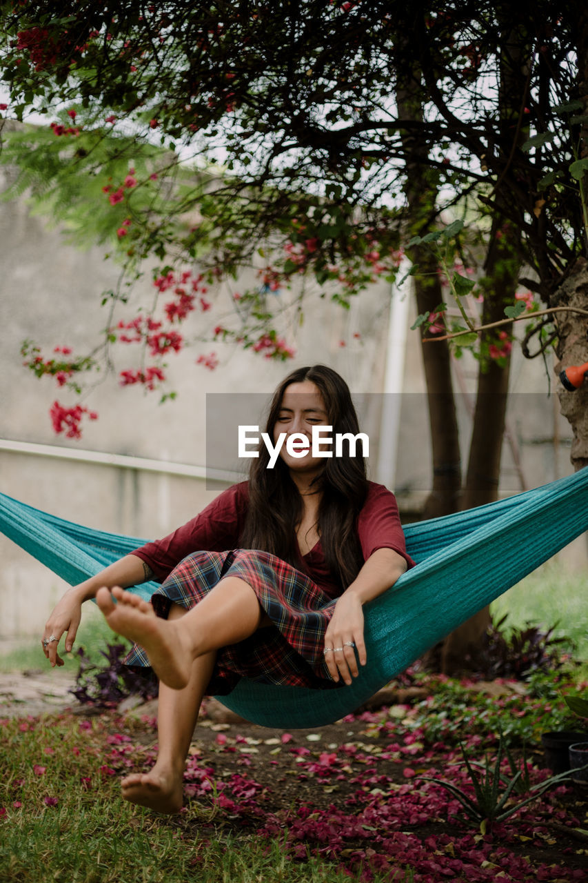 Portrait of smiling young woman sitting against plants