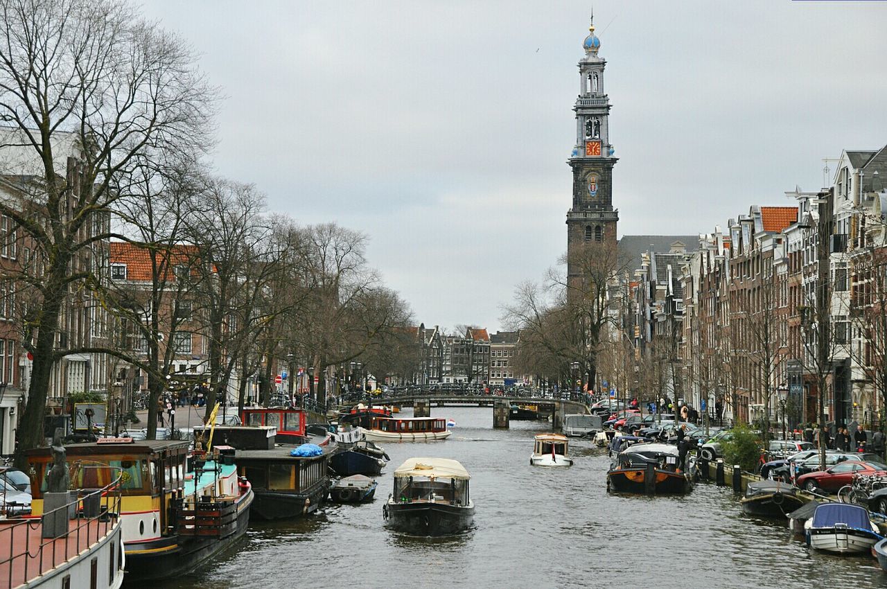 Boats in canal along buildings and bare trees
