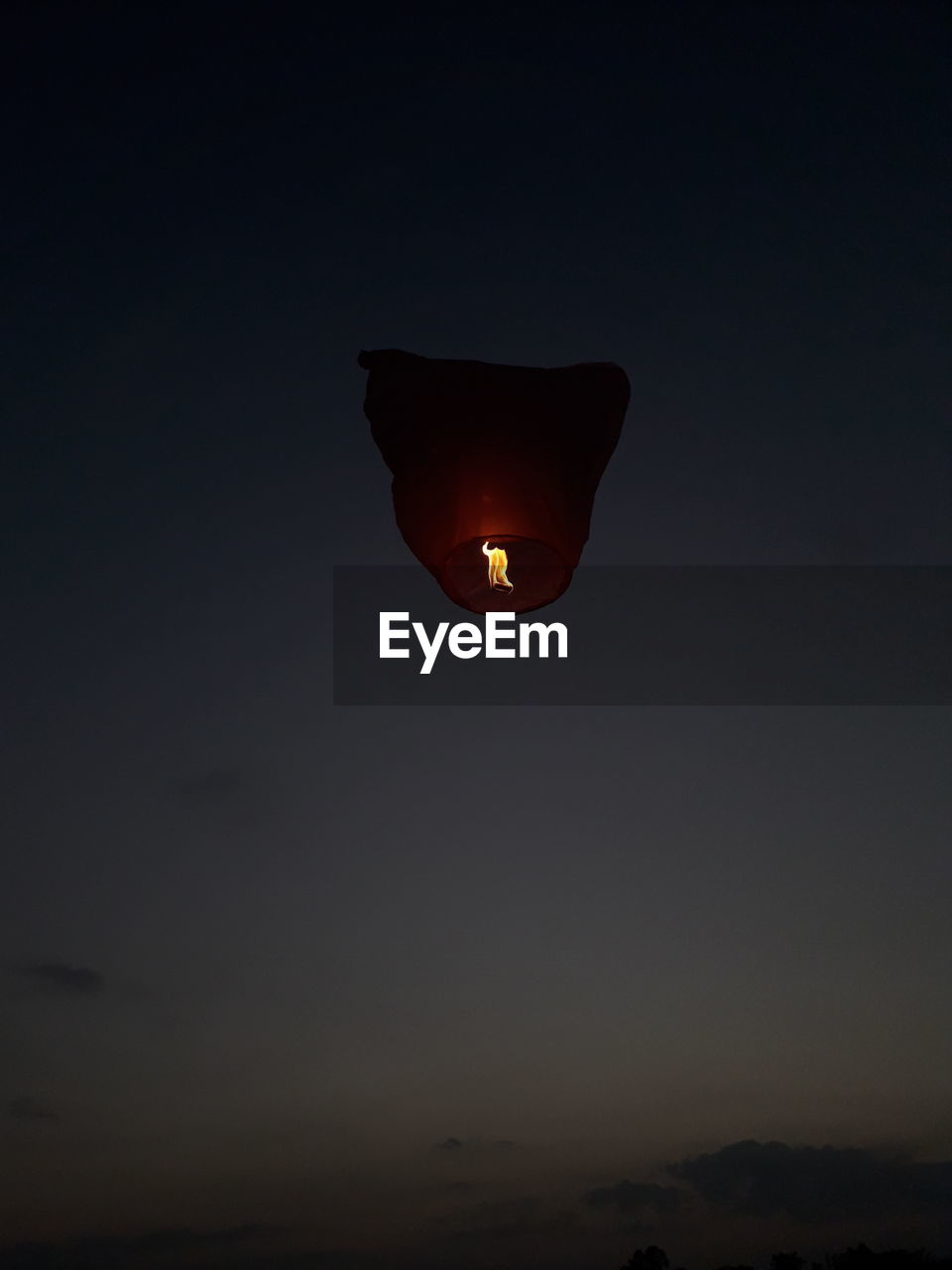 LOW ANGLE VIEW OF ILLUMINATED LIGHT AGAINST SKY AT SUNSET