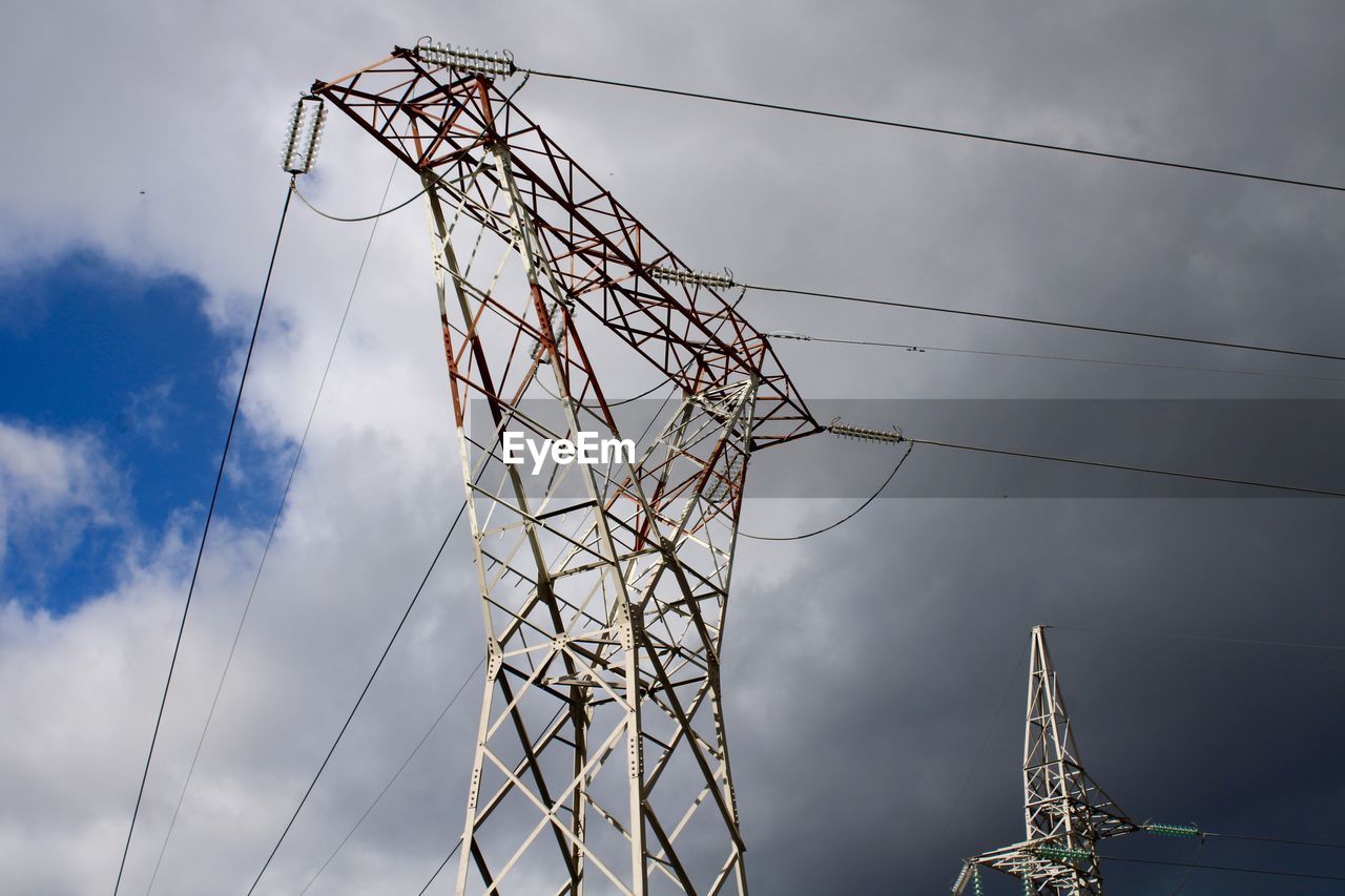 Low angle view of electricity pylon with sky background