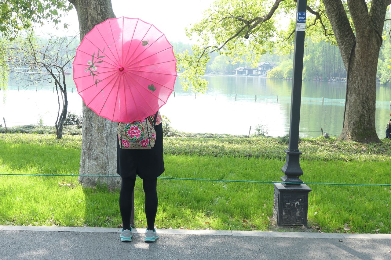 REAR VIEW OF WOMAN HOLDING UMBRELLA DURING RAIN