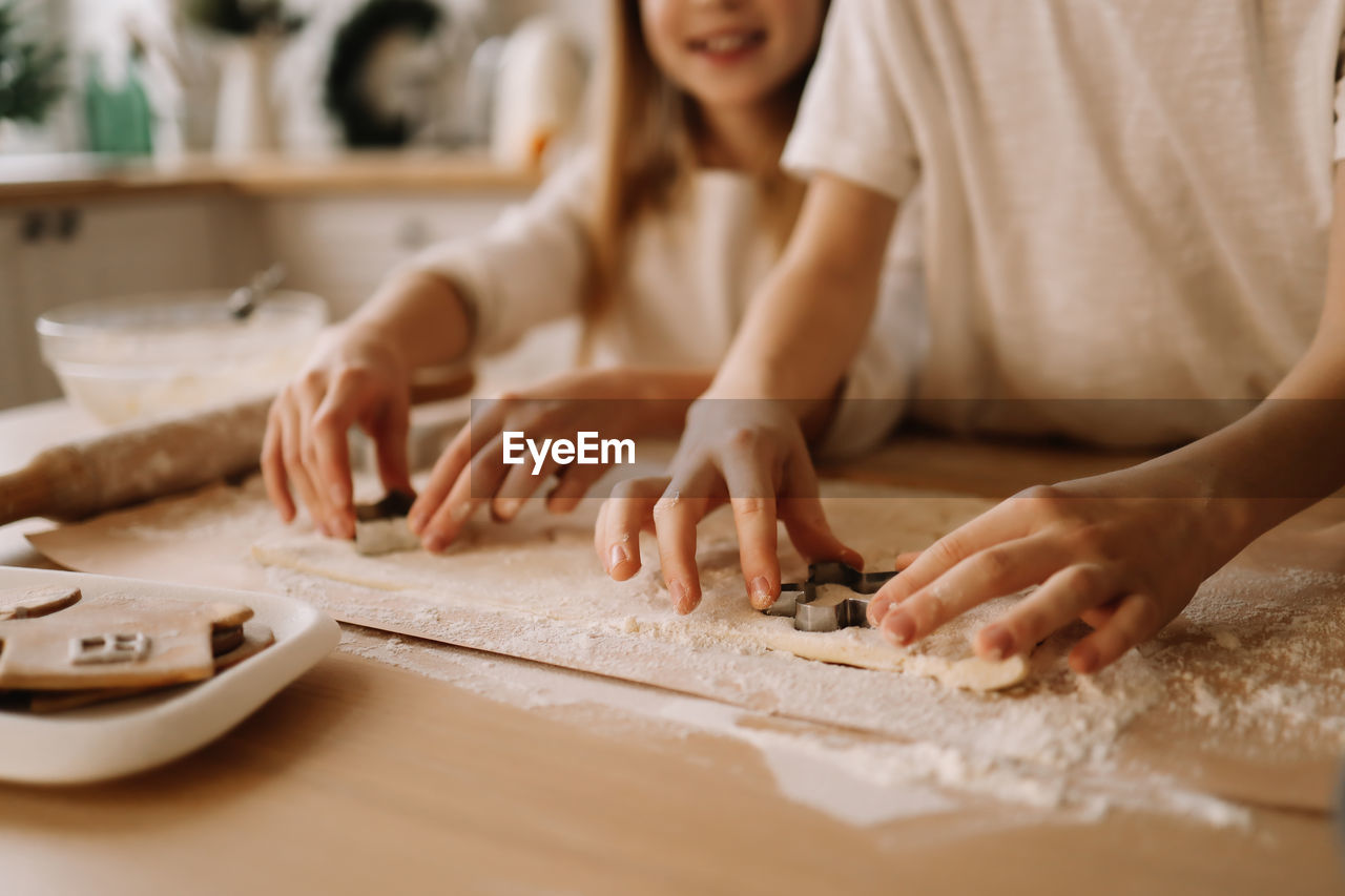 A happy family together carve festive cookies out of dough at christmas in the kitchen at home