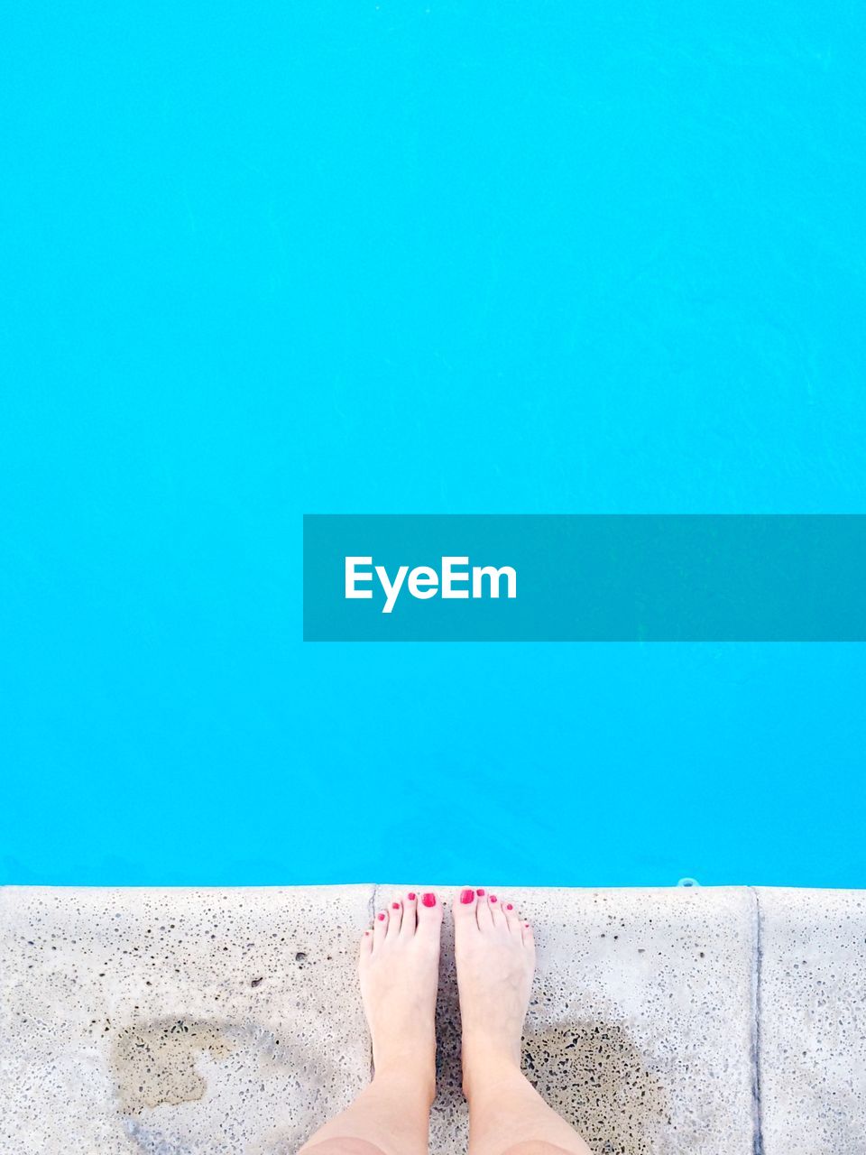 Low section of woman standing in front of swimming pool