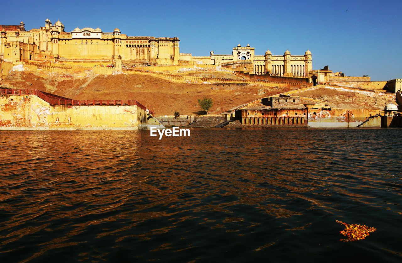 View of maota lake by amber fort against clear blue sky