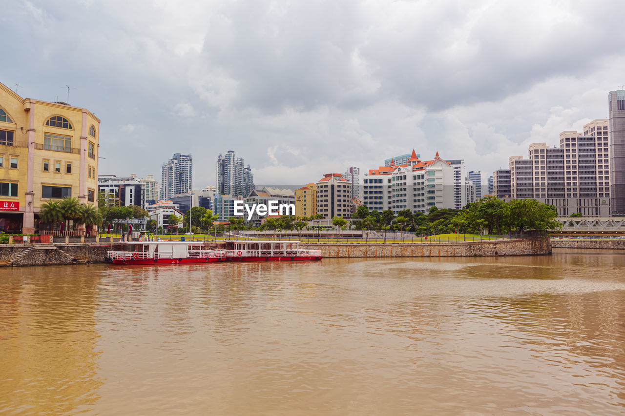 buildings by river against sky in city