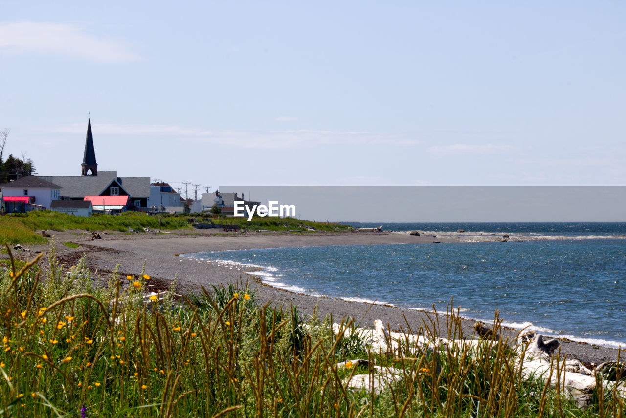 Scenic view of sea by a village in gaspesie against sky