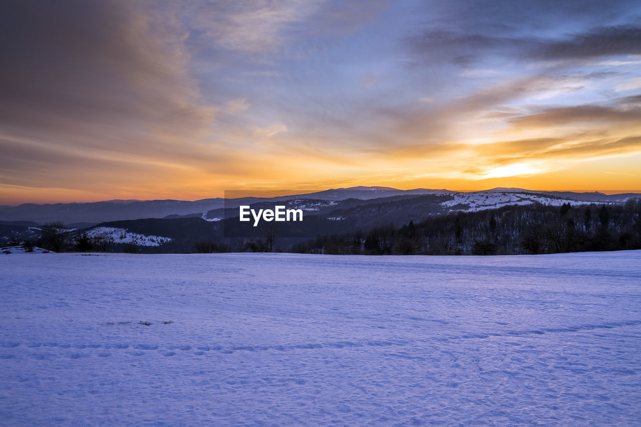 Scenic view of snowcapped mountains against sky during sunset