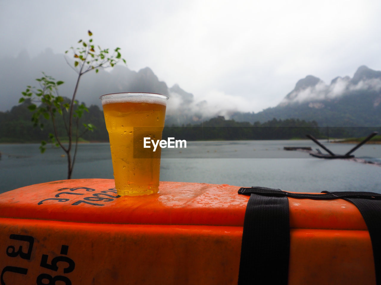 Close-up of beer on container by lake