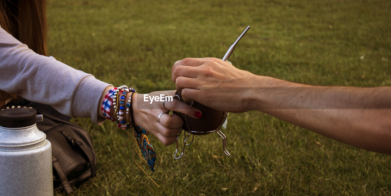 Cropped image of friends sharing yerba mate at park