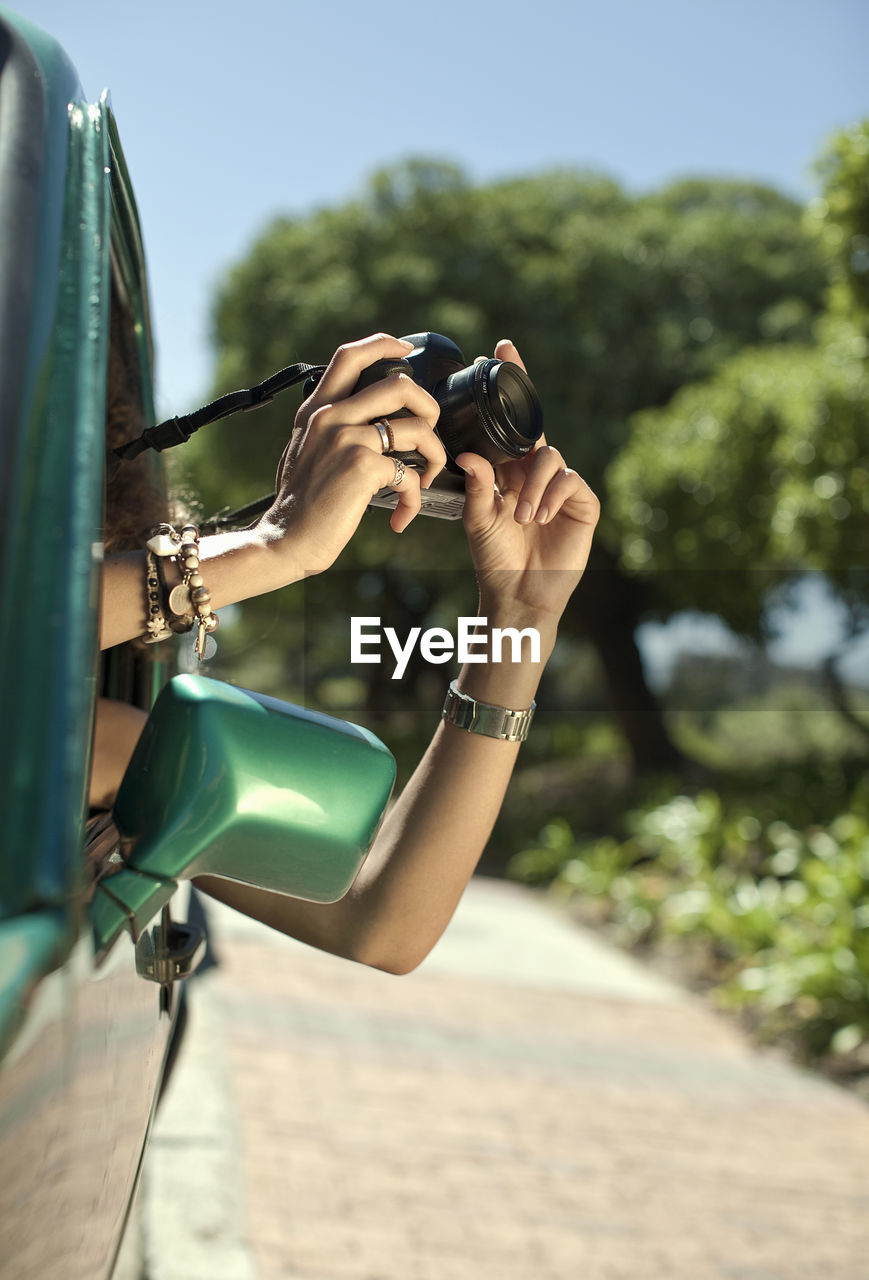 Woman photographing with camera through car window