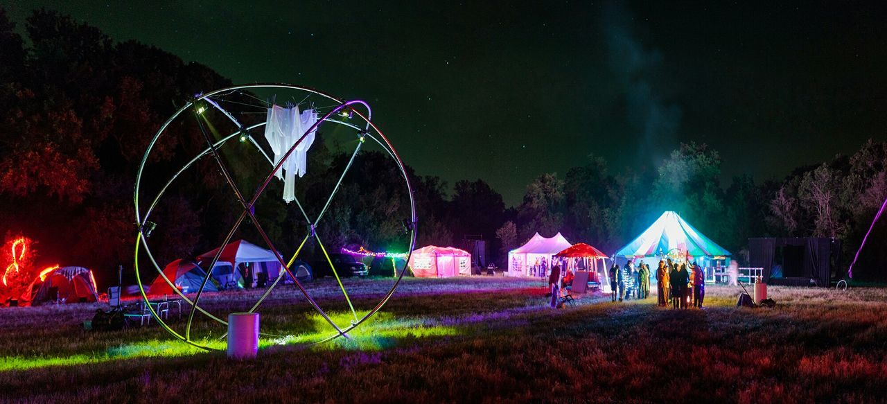 Illuminated tents on landscape at night