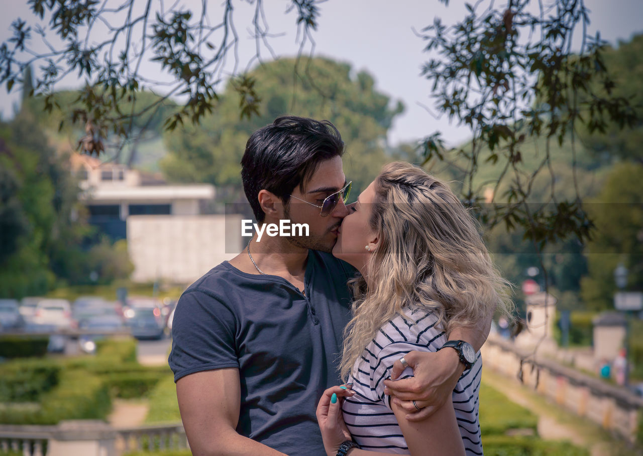 Young couple kissing while standing at park