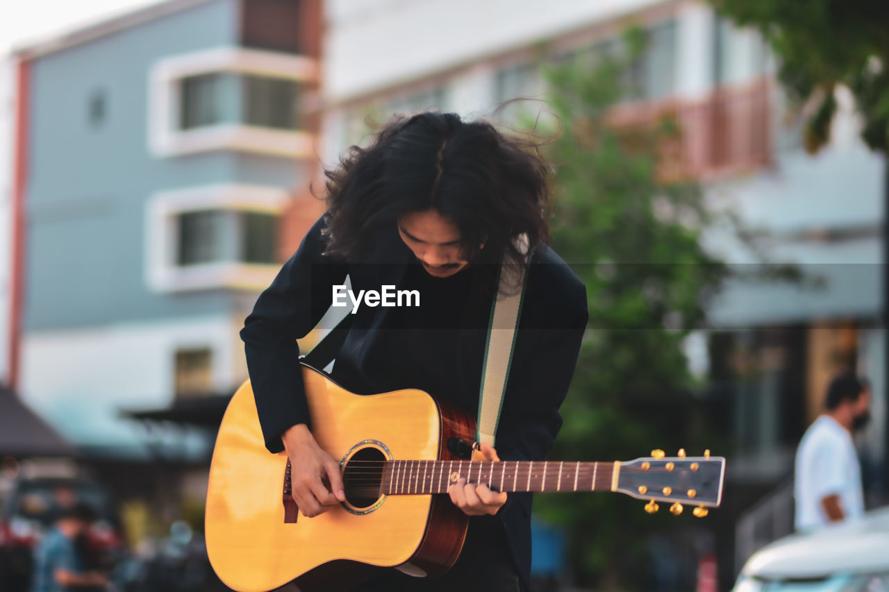 YOUNG WOMAN PLAYING GUITAR AT THE CAMERA