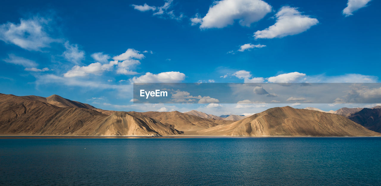 Scenic view of lake and mountains against cloudy sky