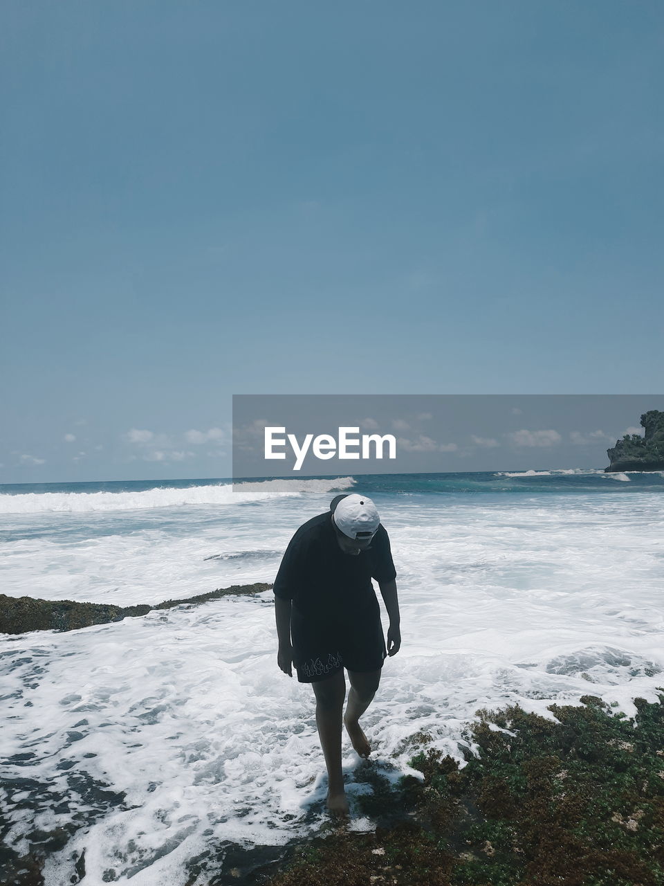 REAR VIEW OF MAN LOOKING AT SEA