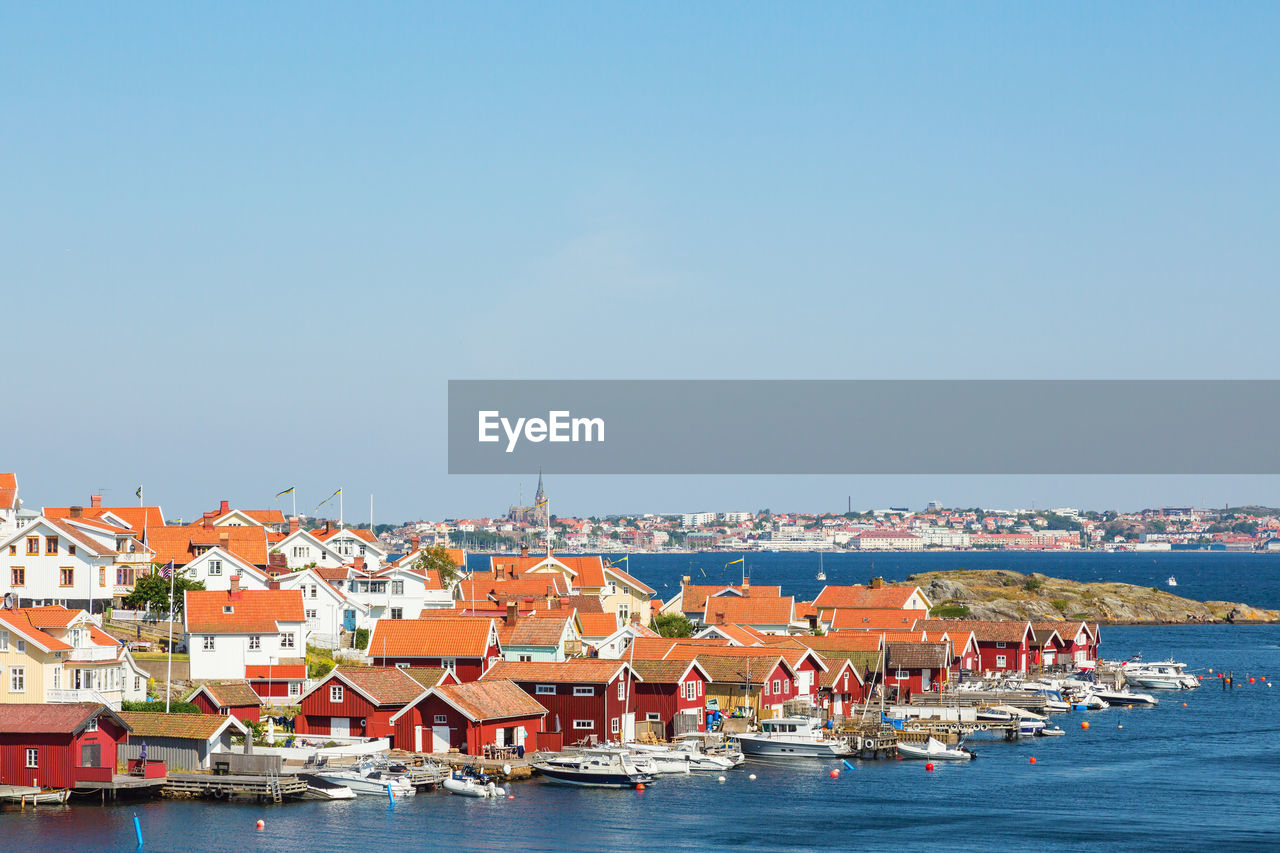 Scenic view of sea by buildings against clear blue sky