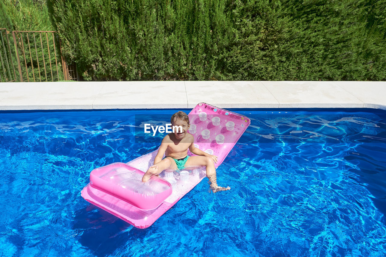 Boy bathing in a pool on a sunny summer day.