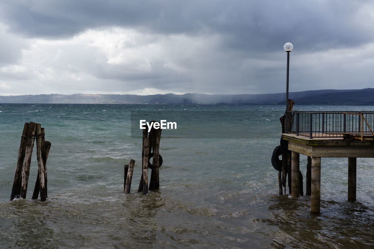 WOODEN POSTS ON SEA AGAINST SKY