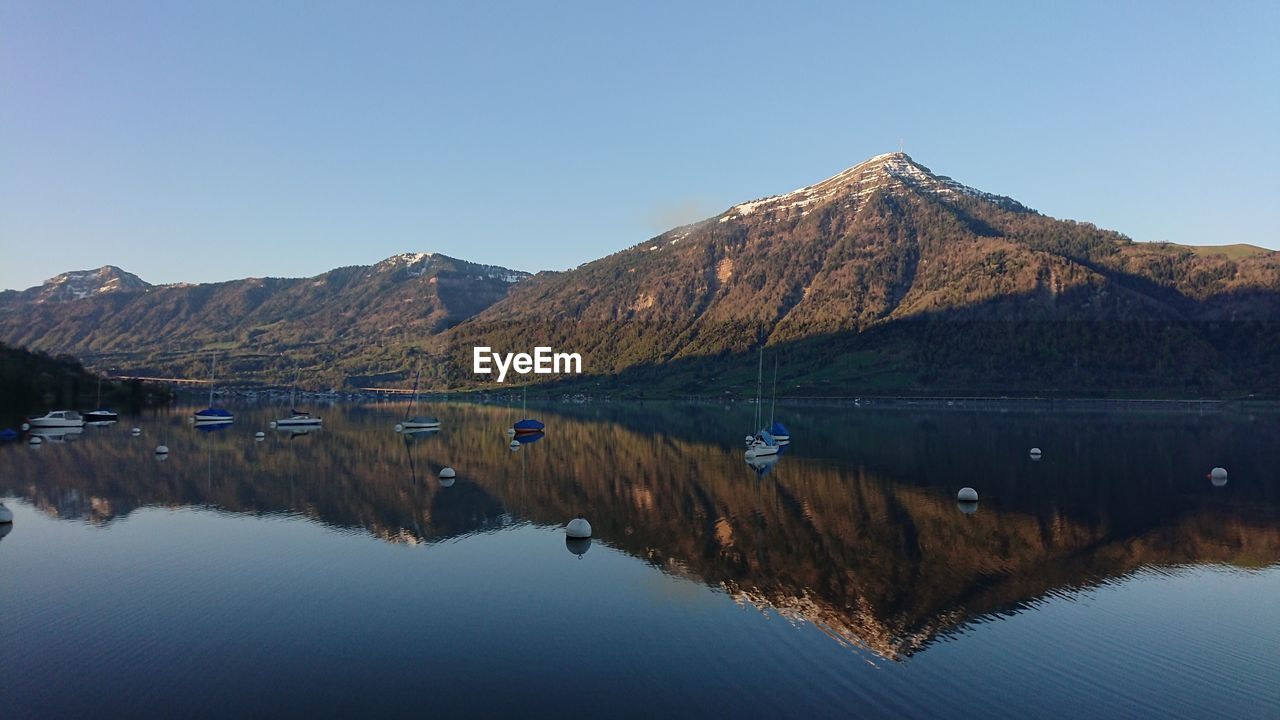 Reflection of mountains in lake against clear blue sky